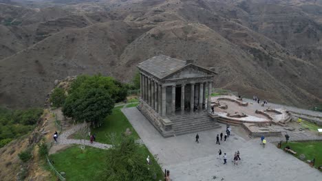 Tourists-visit-Greco-Roman-Garni-Temple-in-Armenia,-aerial-orbits