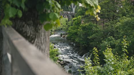 Scenic-view-of-the-Slunjčica-River-flowing-through-lush-greenery-with-a-rustic-bridge-in-Rastoke,-Croatia