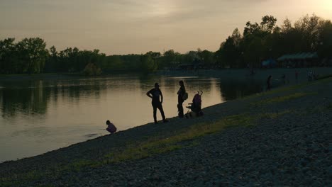 Silhouetted-family-fishing-and-relaxing-by-a-calm-lake-at-sunset-in-Jarun-Lake,-Zagreb
