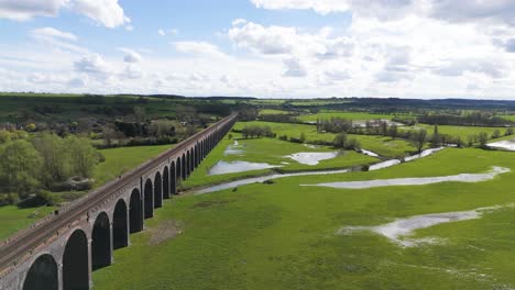 Slow-drone-flight-alongside-Welland-Viaduct-Northamptonshire-also-known-as-the-Harringworth-and-Seaton-Viaduct-on-sunny-day-showing-expanse-of-England’s-longest-viaduct-and-river-and-valley-below