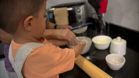 Slow-motion-of-a-small-mexican-latin-boy-sifting-flour-on-a-bowl-with-his-hands-cooking-with-his-father-some-cookies