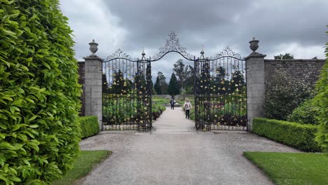 Jardines-Powerscourt-En-Wicklow,-Visitante-Caminando-A-Través-De-Puertas-Ornamentadas-En-Los-Jardines-Amurallados,-Lugares-épicos-De-Irlanda