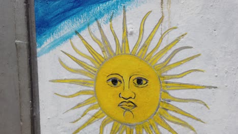 Argentine-flag-painted-in-a-concrete-wall-with-it's-golden-sun-Face-closeup-shot
