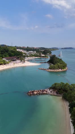 Rotating-aerial-above-the-beautiful-tropical-beaches-of-Sentosa-Island,-Singapore,-vertical-video