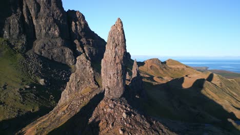 Ancient-volcanic-stone-spire-The-Old-Man-of-Storr-overlooking-distant-coastline-with-long-early-morning-shadows-in-winter