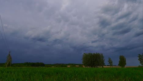 Timelapse-De-Oscuras-Nubes-De-Tormenta-Se-Forman-En-El-Cielo-Sobre-El-Campo-Agrícola-Verde,-Letonia