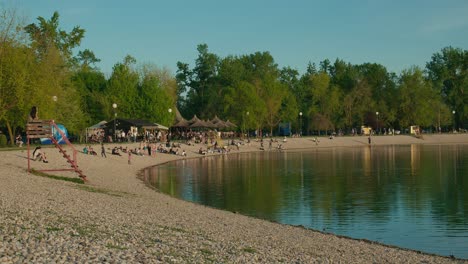 Crowded-lakeshore-with-people-enjoying-the-beach-and-greenery-in-Jarun-Lake,-Zagreb