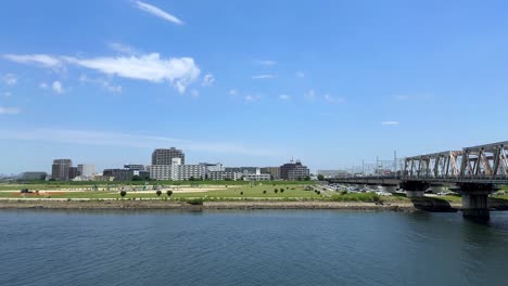 Ein-Malerischer-Park-Am-Flussufer-Neben-Einer-Brücke-Unter-Einem-Klaren-Blauen-Himmel-An-Einem-Sonnigen-Tag