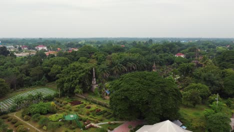 Drone-departing-from-the-"Buddha-Park"-or-"Xieng-Khuan"-and-revealing-the-beautiful-village-of-Deua,-Thanon-Tha,-Vientiane,-Laos