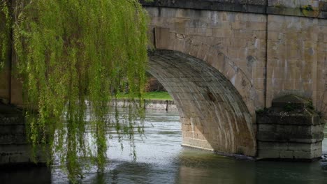 Scenic-view-of-River-Thames-flowing-under-stone-arch-of-bridge-with-weeping-willow-trees-in-the-historic-market-town-and-civil-parish-of-Wallingford,-South-Oxfordshire,-England
