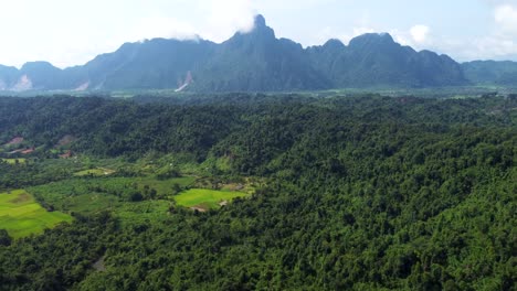 Mountain-range-near-Naka-in-Laos,-and-a-vast-green-field-on-a-cloudy-day