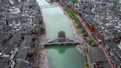 Vista-Aérea-Inclinada-Hacia-Arriba-Del-Puente-De-Nieve-Sobre-El-Río-Tuo-Jiang-En-El-Casco-Antiguo-De-Fenghuang,-China,-Una-Ciudad-Antigua