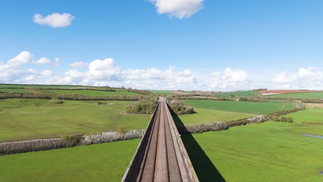 Forward-overhead-drone-flight-following-rail-tracks-of-Welland-Viaduct-Northamptonshire,-also-known-as-the-Harringworth-and-Seaton-Viaduct-showing-England’s-longest-viaduct