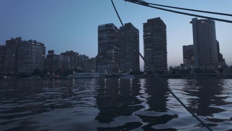 Cairo,-Egypt-as-seen-from-a-felucca-boat-sailing-in-the-Nile-River-at-dusk