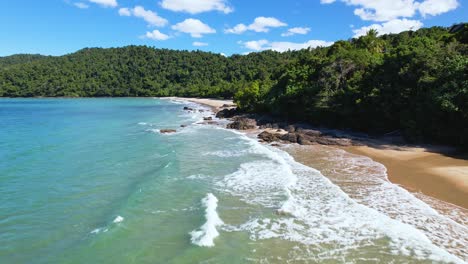 4K-Drone-video-flying-forward-over-the-blue-ocean-waves-crashing-towards-the-white-sand-beach-in-Etty-Bay,-Queensland-Australia