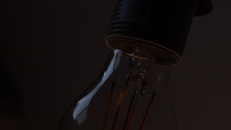 Tilting-down-clear-lightbulb-turning-on-and-off-close-up