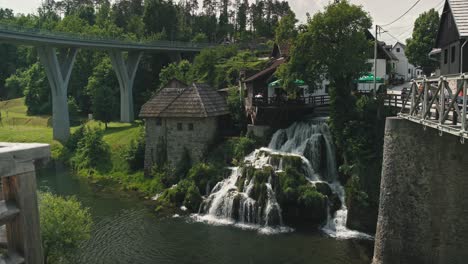 Charming-stone-and-wooden-buildings-with-a-picturesque-waterfall-and-a-bridge-in-Rastoke,-Croatia
