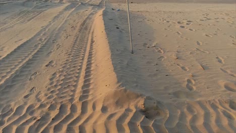 Vista-En-Movimiento-De-Una-Señal-De-No-Nadar-En-Azul,-Amarillo-Y-Rojo-En-Una-Playa-De-Arena-Desierta-Con-Un-Fondo-Claro