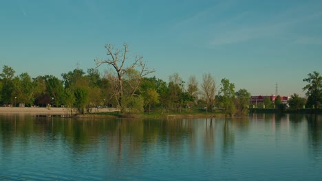 Vista-Panorámica-De-Un-Lago-Tranquilo-Con-Reflejos-De-árboles-Y-Un-Cielo-Despejado-En-El-Lago-Jarun,-Zagreb-Croacia