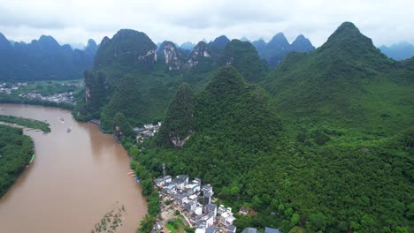 Aerial-panoramic-views-of-mountainous-Xingping-Ancient-town-and-brown-Li-Jiang-River,-China