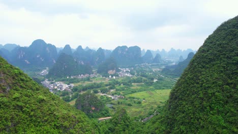 Aerial-pan-down-view-of-a-village-in-Yangshuo-between-the-mountains,-China