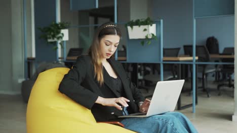 Hübsche-Junge-Frau-In-Business-Kleidung-Sitzt-Mit-Ihrem-Laptop-In-Einem-Stilvollen,-Modernen-Coworking-Büro-Und-Erhält-Eine-Freudige-Nachricht-über-Den-Gewinn