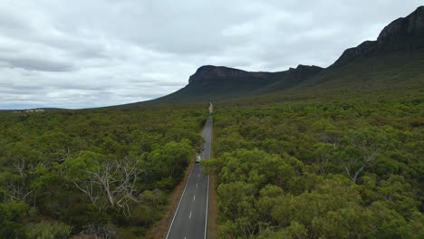 4K-Drone-video-moving-forward-through-the-lush-green-nature-following-a-white-camper-van-through-the-Grampians-National-Park-in-Australia