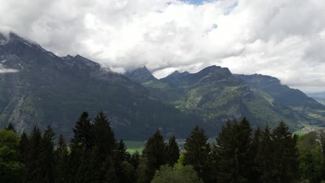 The-scenic-view-of-Glarus,-Switzerland,-as-mountain-peaks-oversee-a-valley-dotted-with-a-charming-residential-area,-epitomizes-the-harmony-between-nature-and-habitation