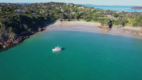 Yacht-In-Der-Bucht-Von-Oneroa-Schwimmt-In-Der-Nähe-Des-Sandstrandes-Mit-Jadefelsen-Auf-Waiheke-Island,-Auckland,-Neuseeland