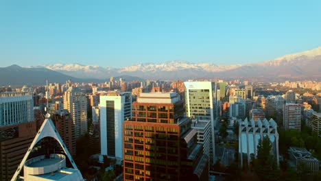 Drohnenüberflug-Rückwärts-über-Die-Wolkenkratzer-Von-Santiago-De-Chile-Mit-Den-Anden-Im-Hintergrund,-Chile