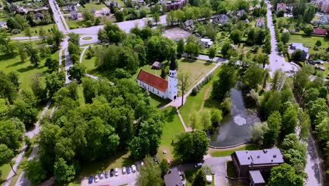 Riga,-Letonia,-Europa---Una-Vista-Panorámica-De-La-Iglesia-Evangélica-Luterana-De-Sigulda-En-Medio-De-Un-Vibrante-Paisaje-De-Parque-Verde---Disparo-De-Drones-En-órbita