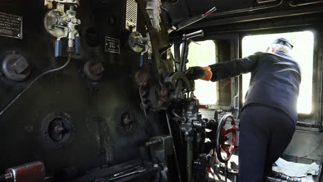 Inside-Steam-locomotive-control-room,-driver-operating-gear-while-looking-out-the-window