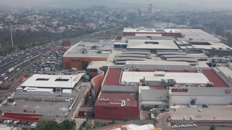 State-of-Mexico,-Naucalpan-de-Juarez,-Drone-Aerial-View-of-Modern-Shopping-Malls-and-Heavy-Pollution-Over-Metropolis---Plaza-Satelite