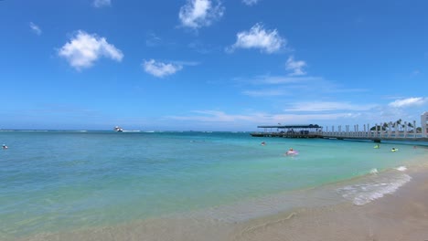 Vista-En-Cámara-Lenta-De-Suaves-Olas-Rompiendo-En-La-Playa-Al-Lado-Del-Muelle-En-Waikiki,-Hawaii