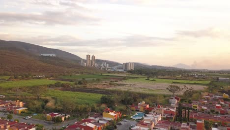 Luftaufnahme-Einer-Drohne-In-Morelos,-Mexiko,-Mit-Betonindustrie-In-Der-Nähe-Einiger-Häuser-Bei-Sonnenuntergang-Und-Grünen-Bergen