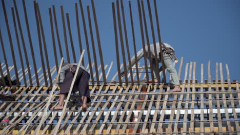 Zwei-Barfüßige-Vietnamesische-Männer-Bauen-An-Einem-Sonnigen-Tag-Das-Dach-Eines-Hauses