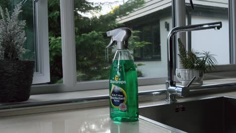 Close-up-Medium-shot-of-spray-disinfectant-brand-at-kitchen-sink-by-window