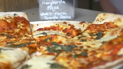 Slow-motion-tilt-down-on-fresh-baked-thin-crust-margherita-pizza-with-chefs-in-background