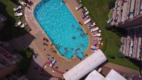 Top-view-drone-shot-of-swimming-pool-in-hotel-complex-with-kids-playing