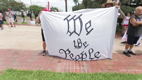 American-patriot-holding-a-"We-The-People"-banner-at-a-"Free-Our-Patriots"-rally-in-Tallahassee,-for-editorial-purpose