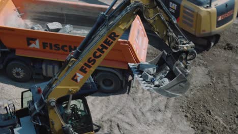Excavator-digging-stone-and-loading-into-truck-on-construction-site-CloseUp