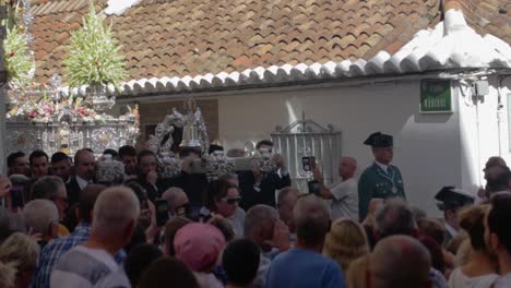 a-large-amount-of-men-carrying-a-huge-silver-statue-of-the-holy-maria-with-nice-decoration-in-the-streets-of-a-traditional-small-town-fuengirola