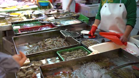 Local-fishmonger-selling-seafood-at-the-live-fish-market-in-Hong-Kong