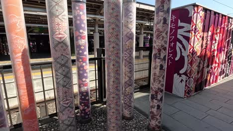 Kyoto,-Japan---The-Kimono-Forest-at-Arashiyama-Station-Features-Poles-Adorned-With-Traditional-Japanese-Fabrics---Sideways-Shot