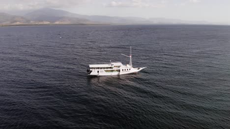 Barco-Turístico-Anclado-Junto-A-Pulau-Bedil,-Una-Pequeña-Y-Hermosa-Isla-Indonesia-Frente-Al-Escudo-De-Lombok,-Vista-Aérea