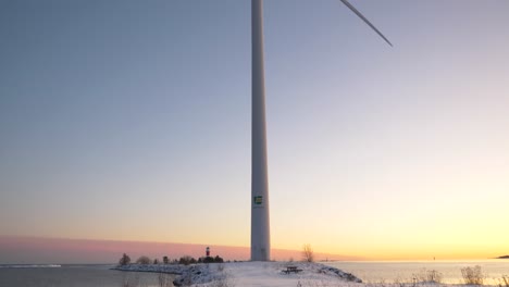 Close-up-tilting-shot-of-a-wind-turbine-slowly-spinning-during-a-beautiful-sunset-sunrise