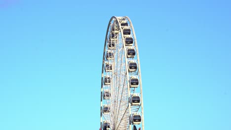 Tourist-attraction,-channel-seven-wheel-of-Brisbane,-ferris-wheel-slow-spinning-against-beautiful-blue-sky-on-a-sunny-day-at-South-bank-parklands,-Queensland,-Australia