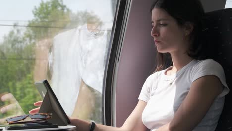 Beautiful-woman-passenger-reading-eBook-on-train-journey,-serene-and-thoughtful