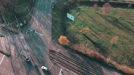 Flying-over-crossroad-of-a-technology-park-with-cars-passing-by-with-sunlight-and-shadow-of-surrounding-buildings-and-trees