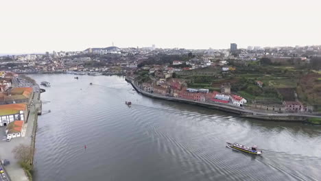 Flyover-view-of-Rabelo-boats-travelling-on-Douro-river,-Oporto